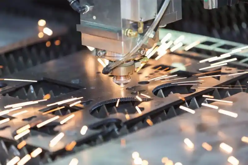 Laser cutting machine slicing through metal sheet with sparks flying in a manufacturing setting